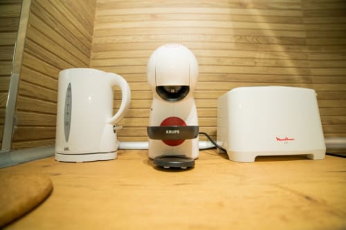 Electrodomésticos en ML Apartments Valencia: hervidor blanco, cafetera Krups y tostadora Moulinex sobre encimera de madera