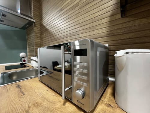 Cocina moderna en ML Apartments Valencia con microondas de acero inoxidable, hervidor blanco y muebles de madera