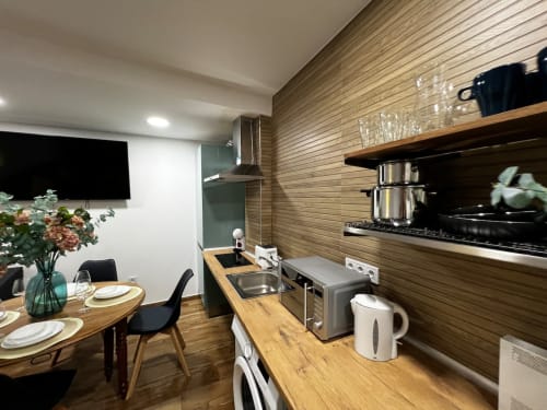 Cocina y comedor modernos en ML Apartments Valencia con acabados de madera, electrodomésticos de acero inoxidable y mesa de comedor