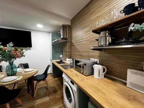 Cocina moderna con encimeras de madera y zona de comedor en ML Apartments Valencia, equipada con electrodomésticos y mesa de comedor