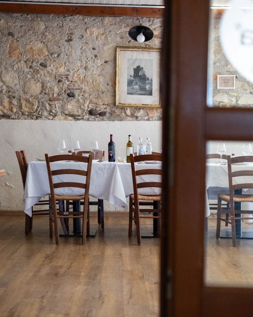 Rustic dining room at Corte Pellegrini B&B in Verona with stone walls, wooden chairs, white linens