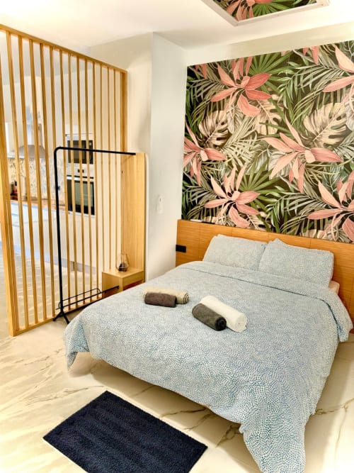Moderno dormitorio en Valencia con cama de madera, papel tapiz de hojas tropicales y piso de mármol claro en ML