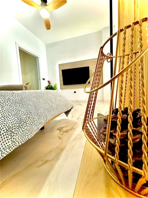 Dormitorio moderno en apartamento de Valencia con ventilador de techo de madera, cama estampada, TV de pantalla plana y pisos de mármol