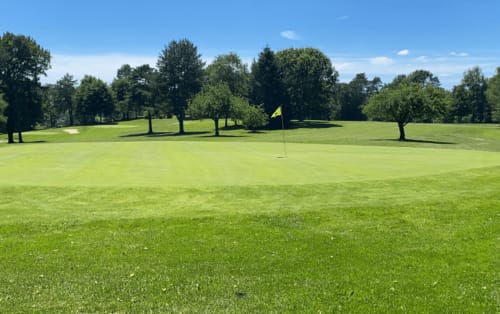 Golf course green at Résidence hôtelière du Coiroux in Aubazine with trees and yellow flag