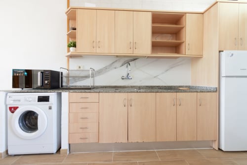 Modern kitchen with light wood cabinetry, marble backsplash, and appliances in Home Stay Gran Canaria room