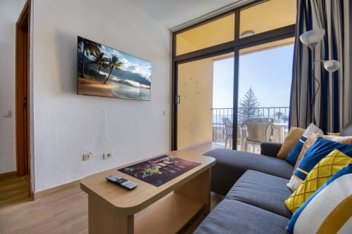 Modern apartment living room with sea view balcony, flat-screen TV, and comfortable seating at Homestaygrancanaria, Las