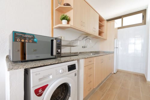 Modern kitchen at Home Stay Gran Canaria with microwave, washer, stovetop and granite countertops in Las Palmas