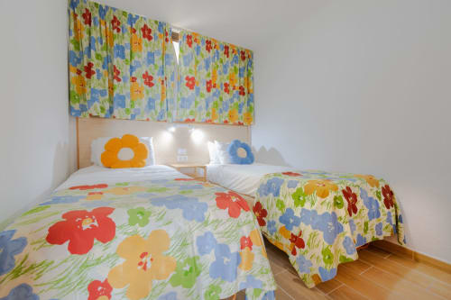 Colorful twin bedroom at Home Stay Gran Canaria with floral bedding, cloud-shaped pillows, and matching curtains in Las