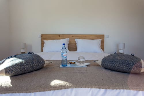 Quarto moderno em Cerro da Campaniça com cabeceira de madeira, almofadas brancas, garrafa de água e vistas para as montanhas em Santiago do