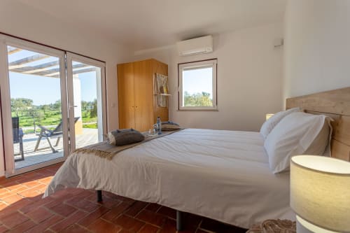 Quarto luminoso em Cerro da Campaniça com cama queen, guarda-roupa em madeira e terraço com vista para o interior de Santiago do Cacém