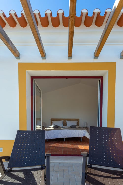 Quarto da Pousada Cerro da Campaniça em Santiago do Cacém com vista de montanha, cama visível pelas portas abertas e lounge da varanda