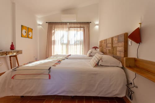 Quarto espaçoso em Cerro da Campaniça com duas camas, cabeceira de madeira e vistas para o jardim através de grandes janelas em Santiago do