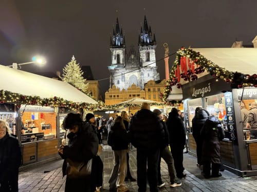 Christmas market in Prague's Old Town Square with illuminated church towers and festive decorations