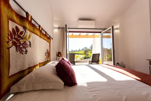 Quarto luminoso em Cerro da Campaniça com vista para jardim, cama de casal, detalhes em borgonha e portas de pátio para o campo