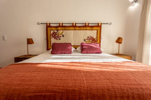 Quarto na Cerro da Campaniça com colcha laranja, cabeceira de madeira com almofadas burgundy e vista para o jardim em Santiago do