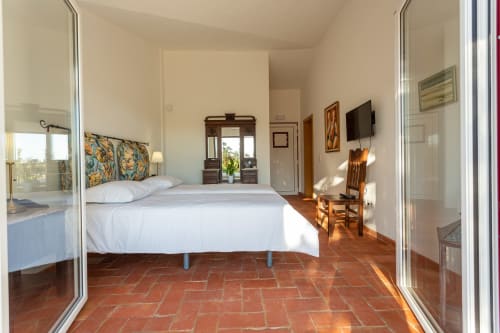 Quarto espaçoso com cama branca, azulejos de barro e vista para o jardim em Cerro da Campaniça B&B em Santiago do Cacém, Portugal