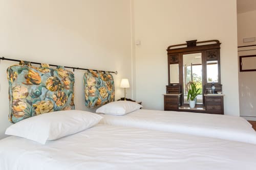 Quarto luminoso na Quinta de Cerro da Campaniça em Santiago do Cacém com cabeceira floral, roupa de cama branca e penteadeira de madeira