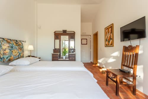 Quarto espaçoso no Cerro da Campaniça B&B com camas individuais, móveis de madeira e vista para o jardim em Santiago do Cacém