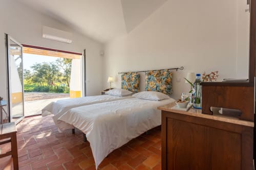Quarto luminoso em Cerro da Campaniça com duas camas, vista para o jardim, piso em terracota e portas que abrem para Santiago do