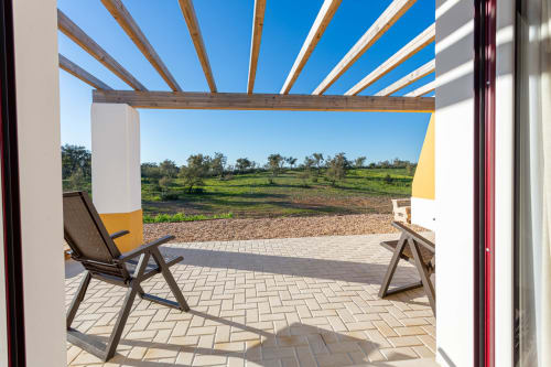 Pérgola de madeira sombreando pátio com espreguiçadeiras com vista para jardins rurais em Cerro da Campaniça, Santiago do Cacém