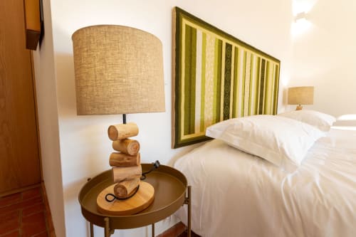 Quarto moderno em Cerro da Campaniça com roupa de cama branca, luminária de cabeceira em madeira e quadros com padrões listrados em Santiago do Cacém