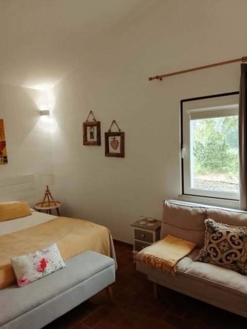 Quarto aconchegante na Pousada Cerro da Campaniça em Santiago do Cacém com vista para o jardim, móveis de madeira e iluminação aquecida