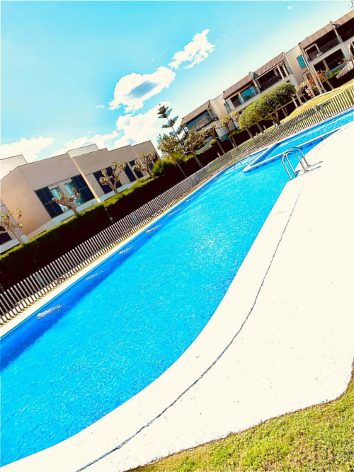 Piscine bleu scintillante avec plage blanche au complexe Sant Jordi, immeuble moderne avec balcons sous ciel dégagé