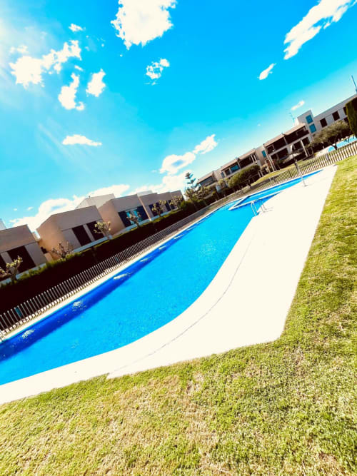 Piscine courbe bleue avec terrasse blanche au complexe Sant Jordi sous ciel dégagé