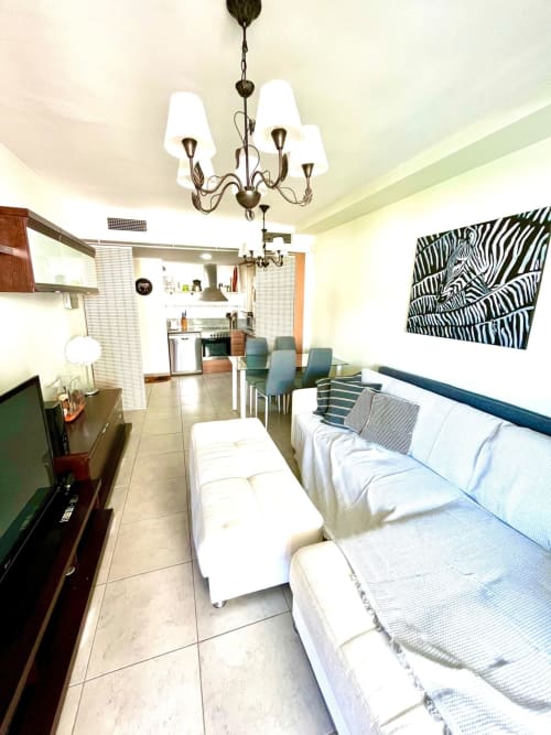 Salon moderne d'un appartement avec canapé, télévision, cuisine et salle à manger chez Home Guardian Services Sant Jordi