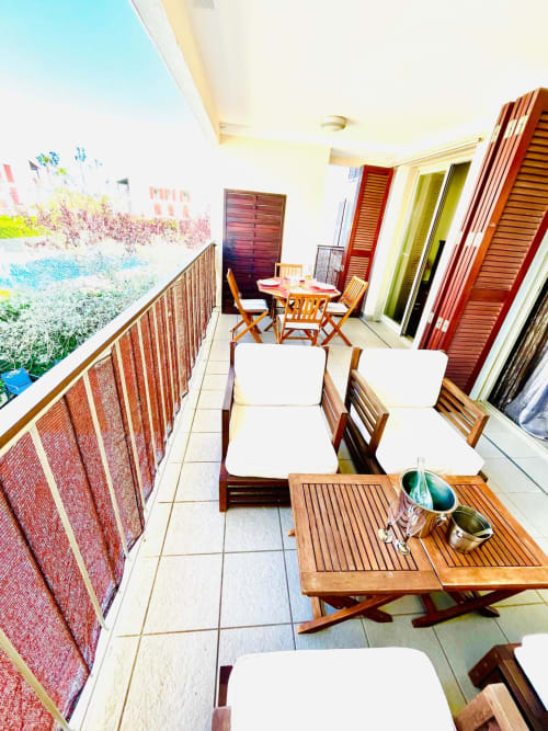 Terrasse balcon avec mobilier en bois et vue sur la piscine de l'appartement Home Guardian Services à Sant Jordi