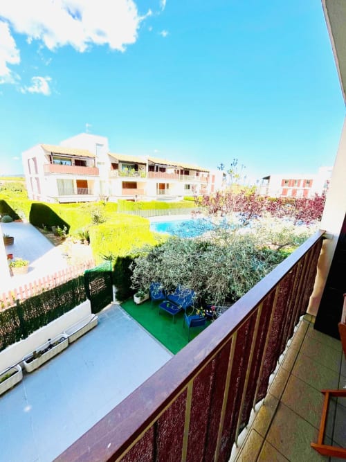 Appartement moderne avec balcon donnant sur la piscine du complexe, jardins verdoyants et architecture contemporaine à Sant Jordi