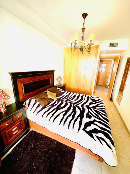Chambre moderne du Home Guardian Services à Sant Jordi avec literie rayée zèbre, mobilier en bois et vue sur la piscine