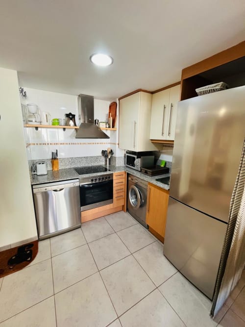 Cuisine moderne de l'appartement Sant Jordi avec électroménagers en acier inoxydable, comptoirs en granit et carrelage