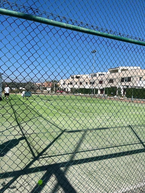 Court de tennis de la propriété Sant Jordi avec bâtiment résidentiel et ciel bleu dégagé en arrière-plan