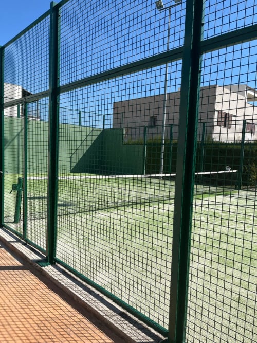 Court de tennis vert avec filet au domaine Sant Jordi, surface en terre battue et bâtiment en arrière-plan