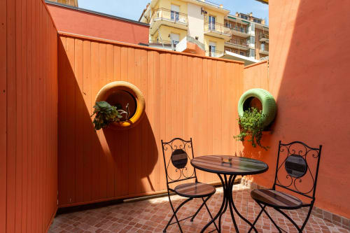 Accogliente patio di Casa Scola Loano con mobili da bistrot, fioriere da pneumatici e muri in terracotta a Loano, Italia