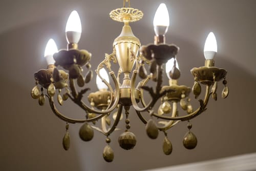 Elegante lampadario in ottone con cristalli pendenti e lampadine a LED stile candela nella camera Pippo di Casa Scola Loano, Liguria