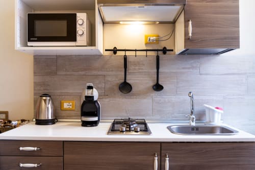 Compact kitchenette in Casa Scola Loano Angetto room with microwave, gas stove, sink, and coffee maker