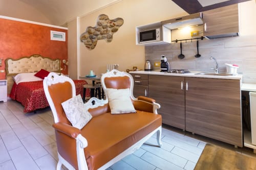 Casa Scola Loano Angetto room with orange baroque chair, kitchenette, red bed and beige headboard