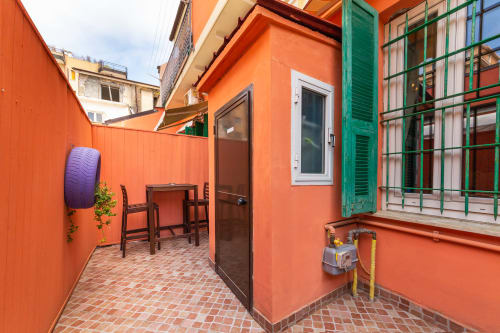 Bright orange patio at Casa Scola Loano with green window shutters, door, and rustic brick flooring in Loano