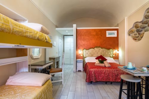 Angetto room at Casa Scola Loano with bunk beds, queen bed, and orange accent wall in Loano