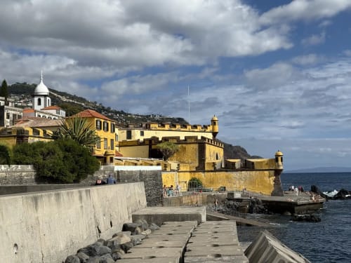 A Vila Sereia Dourada, sua fortaleza amarela com vista para a costa rochosa e porto de Ribeirinha em Portugal