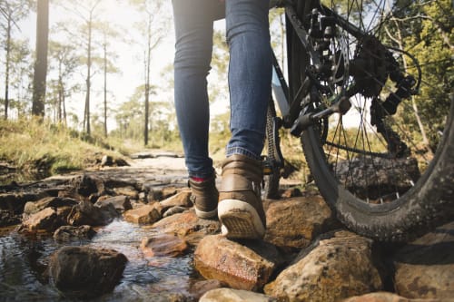 Mountain biker crossing rocky stream near Les Cabanes des Marchous, Granges-Aumontzey
