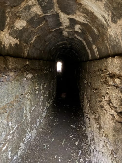 Túnel de pedra escura com abóbada arqueada e luz ao fundo, Golden Mermaid Villa, Ribeirinha Portugal