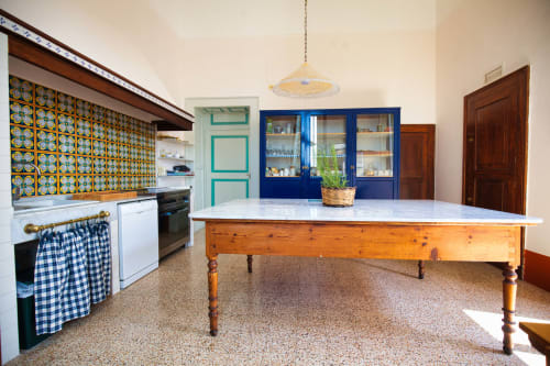 Cucina spaziosa di Villa Ceci B&B ad Andria, Italia, con mobili blu, piastrelle decorative, tavolo in legno e pietra