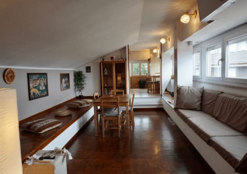 Moderno appartamento in mansarda a Velletri con pavimenti in legno, zona pranzo, divano marrone, arredamento in legno e vista sulla città dalle finestre