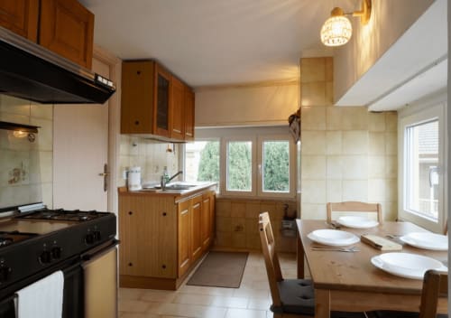 Ampia zona cucina-soggiorno con armadietti in legno, tavolo da pranzo e grandi finestre con vista sulla città a Di Leonardo Bnb a Velletri