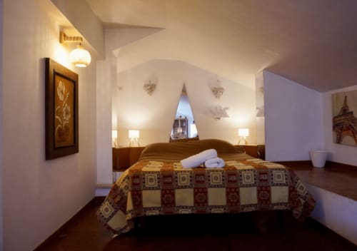 Camera da letto accogliente in soffitta al B&B Di Leonardo a Velletri con soffitto spiovente, letto matrimoniale, illuminazione calda e pavimenti in legno