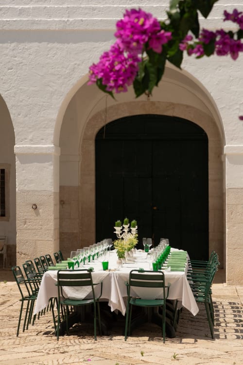 Zona pranzo esterna a Villa Ceci ad Andria con fiori fucsia, tovaglie bianche e sedie verdi