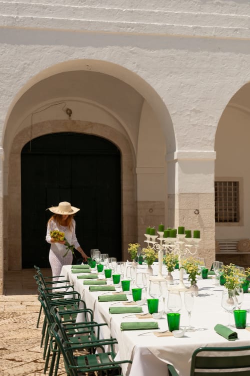 Elegante allestimento per cena all'aperto a Villa Ceci ad Andria con tovaglioli verdi, tovaglie bianche e architettura ad arco.
